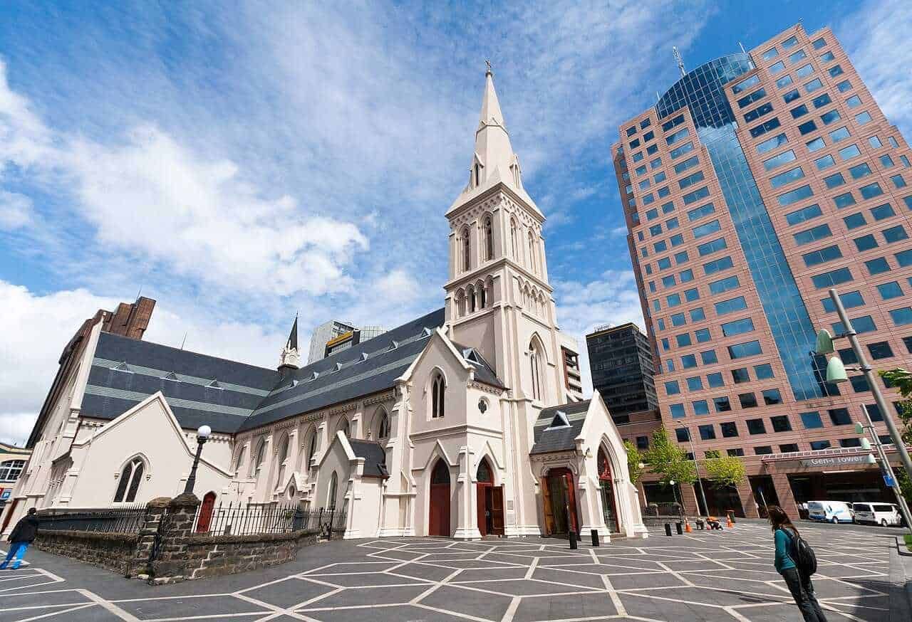 Immagine di una chiesa storica circondata da moderni grattacieli a Auckland, Nuova Zelanda, sotto un cielo sereno. Perfetta combinazione tra architettura antica e moderna.