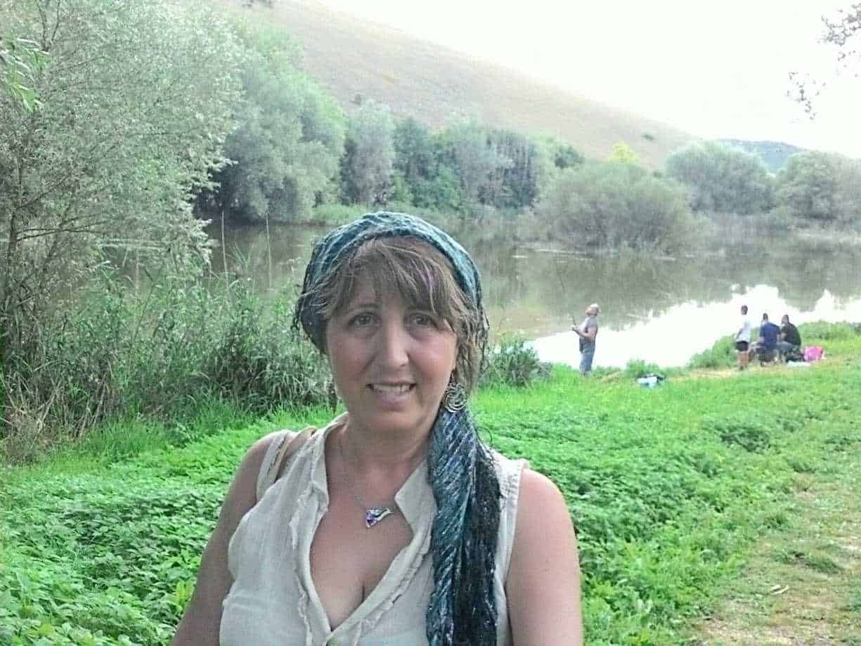 Vita all'aperto sul fiume, donna con sciarpa blu e camicia bianca, paesaggi naturali, incontri tra amici, relax nella natura, attività di pesca, ambiente tranquillo, scenari verdi e serene, escursione all'aperto, ritratto di donna felice.