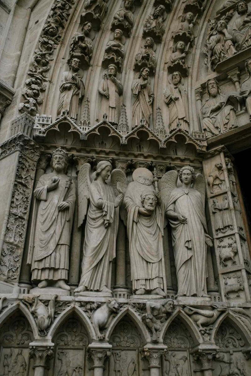 Cos'è il gotico, arte gotica dal classico al moderno 2 Statuaria gotica della facciata della Cattedrale di Notre Dame, rappresentando scene bibliche sui lignei elementi decorativi, con dettagli intricati e figure sacre.