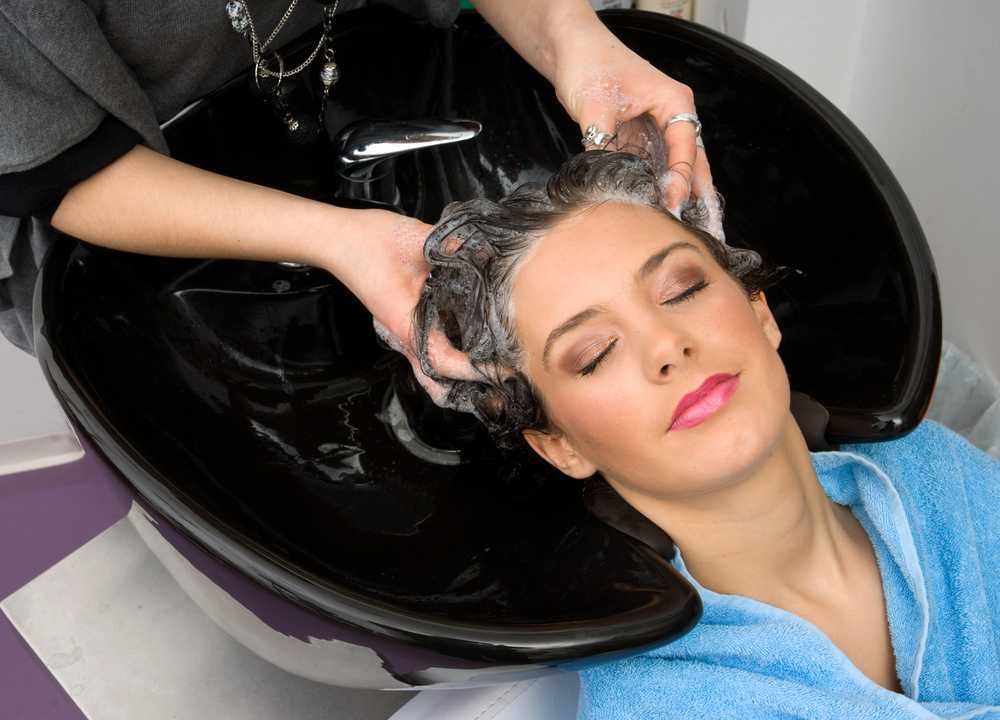 Capelli in fase di lavaggio presso il salone di parrucchiere, donna rilassata ricevendo trattamento di bellezza, cura dei capelli, shampoo professionale, benessere capillare, servizio di bellezza.
