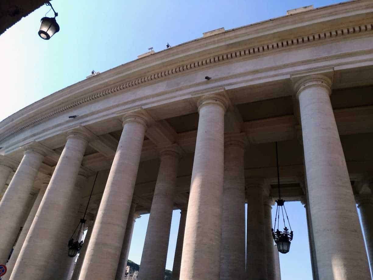 Immagine di un edificio storico con colonne in stile classico, dettagli architettonici e lampioni decorativi, parte della colonna esterna del Colosseo a Roma, simbolo dell'antica architettura romana e turismo culturale in Italia.