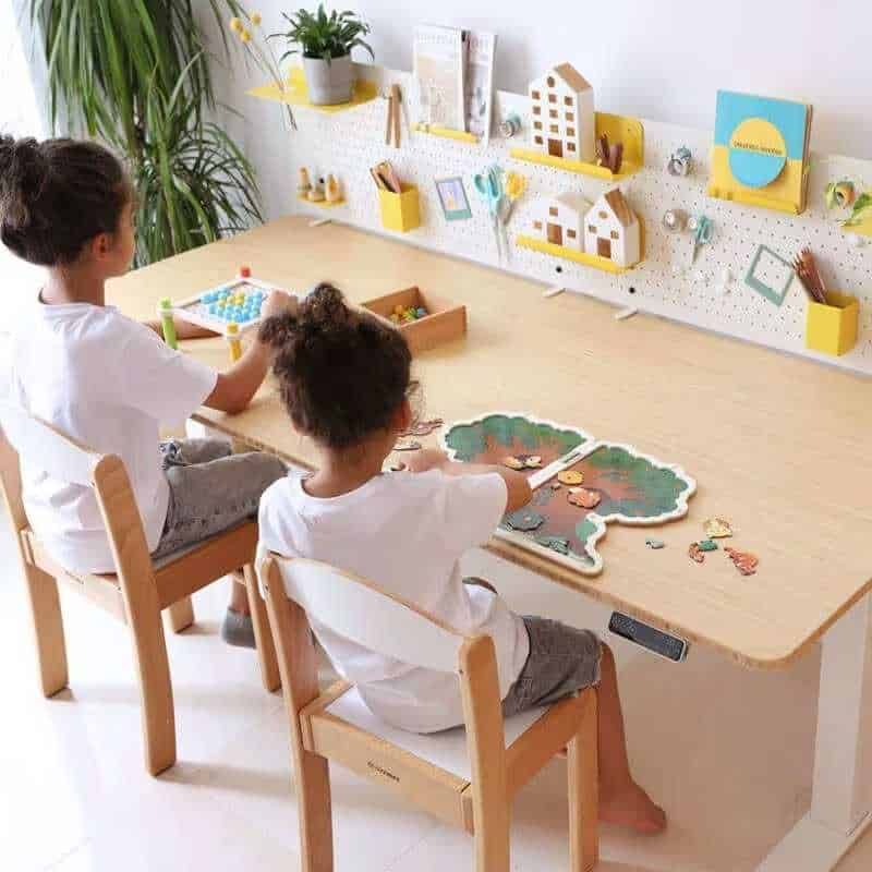Puzzle di legno su tavolo di bambini che giocano, ambiente educativo e creativo, decorazioni per bambini con scatole, libri e piante verdi, spazio di gioco stimolante e colorato, ideale per attività formative e di svago.