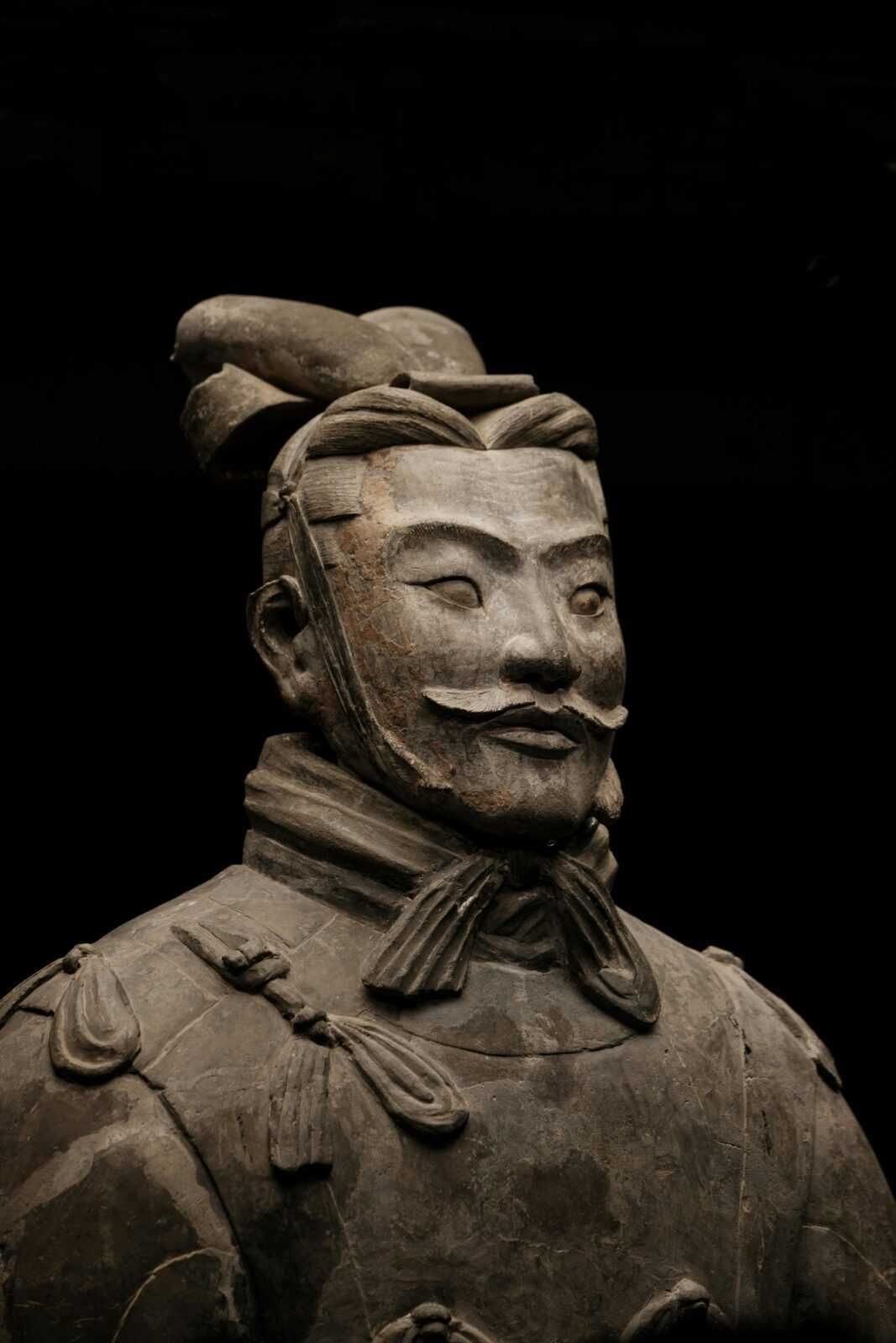 Antica statua in terracotta di un guerriero cinese, dettagliata e restaurata, risalente alla Dinastia Qin, esposta al museo, rappresenta la storia e l'arte dell'antica Cina.