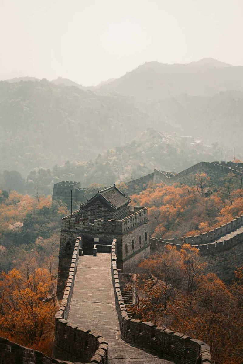 Qin Shi Huang l'imperatore che creò la Cina, libro 5 Fascicolo di immagini della Grande Muraglia Cinese tra le montagne autunnali, ricca di colori caldi, viste panoramiche storiche e architettura antica in un paesaggio naturale suggestivo.
