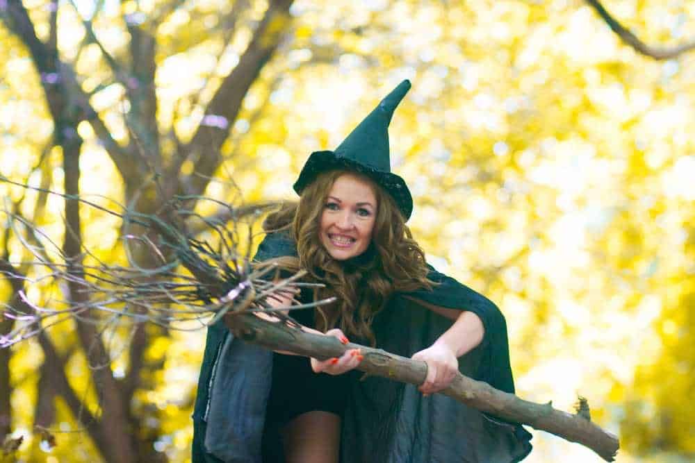 Strega con cappello a punta in un bosco autunnale, scena magica e fiabesca di Halloween e magia, ambientazione misteriosa.