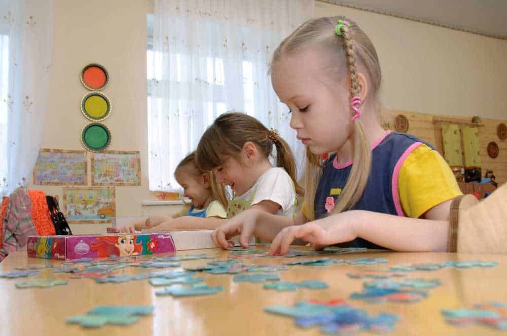 Bambini che giocano con puzzle educativi in classe, attenzione e concentrazione migliorate, attività didattiche per bambini, ambiente scolastico colorato e stimolante.