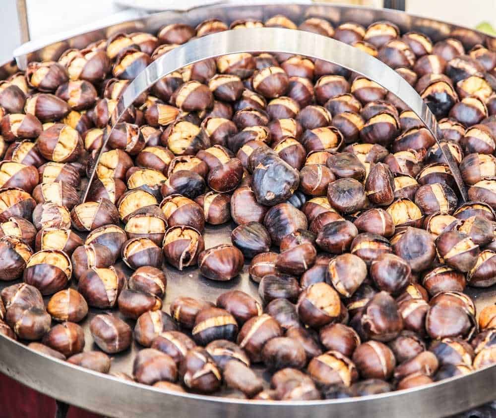 Castagne arrosto su teglia, tradizione autunnale, deliziose castagne cotte al forno, perfette per merenda calda, snack autunnale, ricetta italiana, street food, evento tradizionale, sapore autentico, cibo di strada.