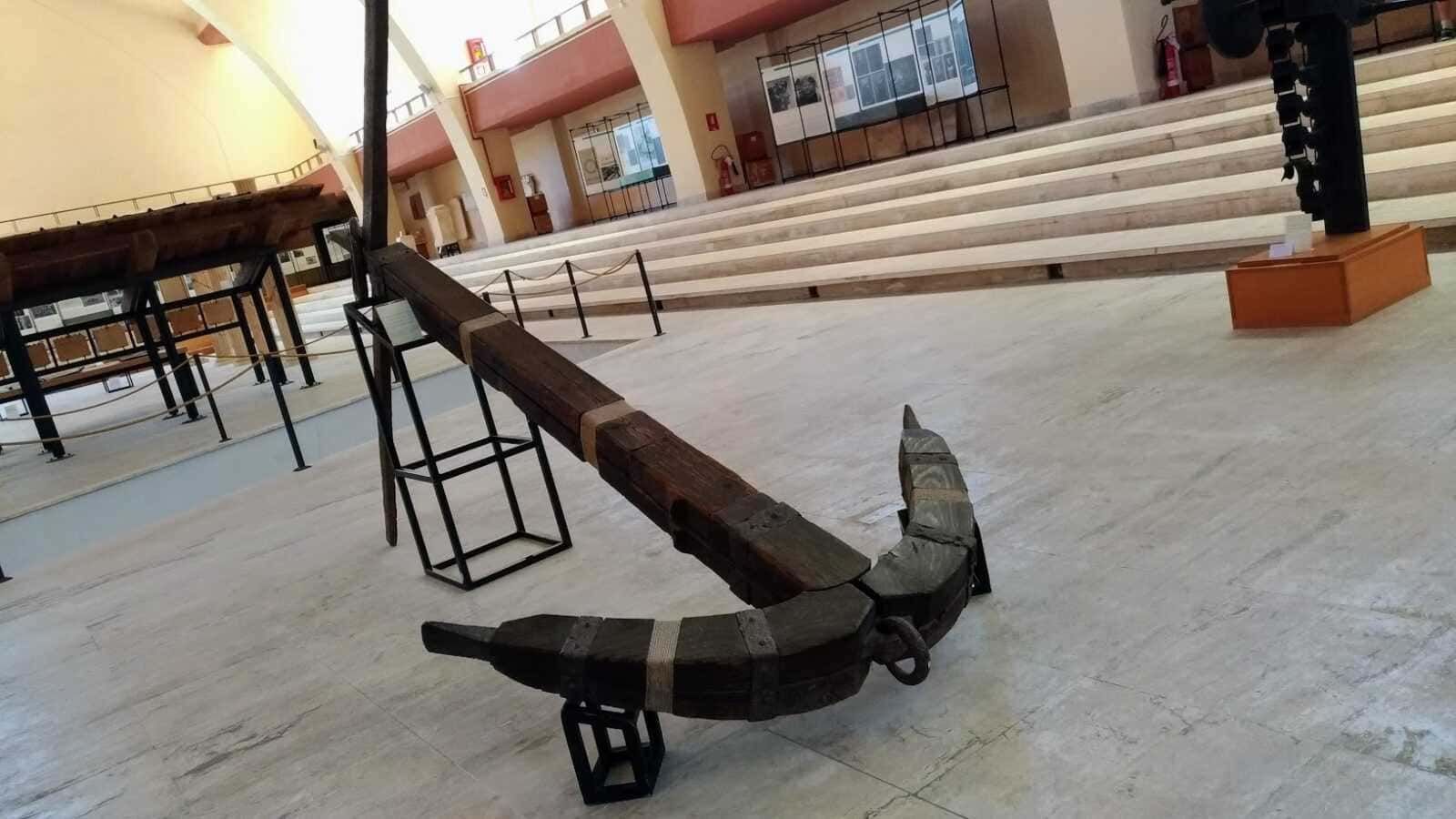 Banco in legno e ferro in un museo storico, ambiente interno con scala e mostre espositive.