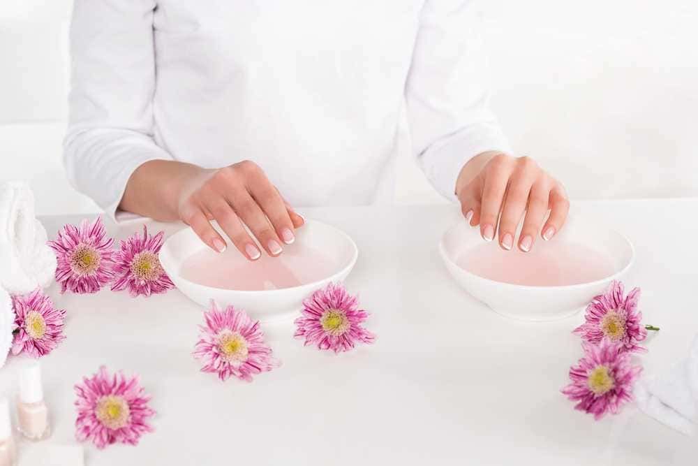 Manicure spa con fiori rosa e prodotti di bellezza, trattamento unghie in ambiente rilassante.