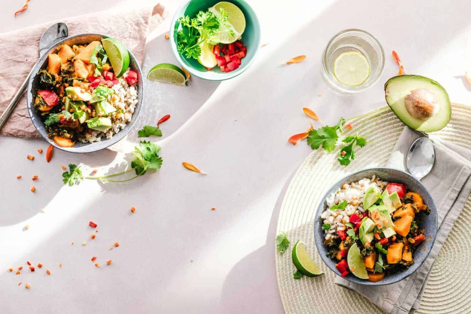 Cibi da evitare per il mal di schiena: Fiocchi di riso integrale con verdure e avocado, piatto salutare con lime e coriandolo, ideali per ricette vegetariane e di dieta equilibrata. Assapora un pasto fresco e nutriente, perfetto per uno stile di vita sano.