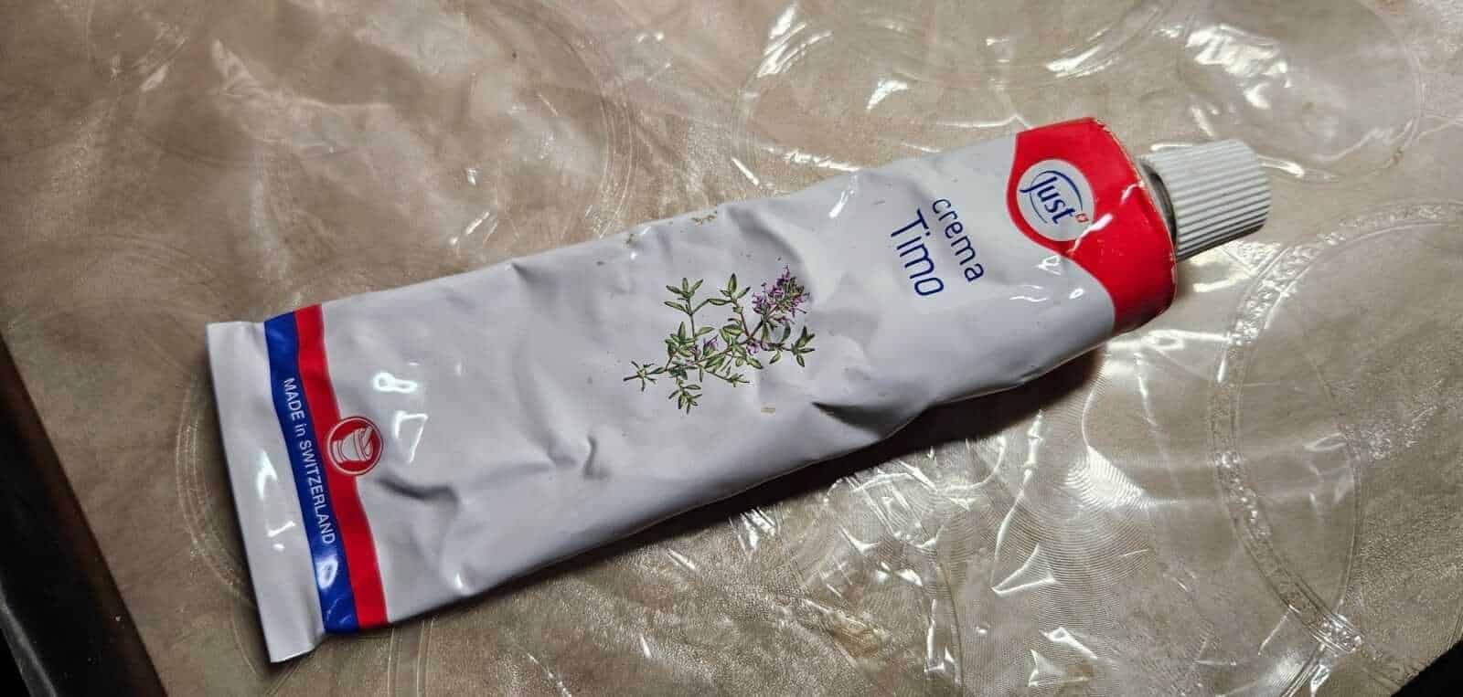 Tè alle erbe in tazza con rametti di timo fresco su tavolo di legno scuro, ambientazione rustica, concetto di infusi naturali, salute e benessere.