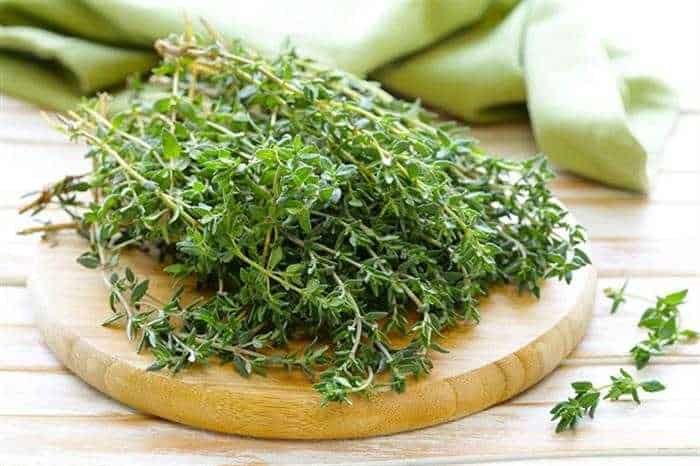 Aromatiche foglie di timo fresco su tagliere di legno, ideale per cucina e ricette. Perfetto per aggiungere sapore e fragranza ai piatti grazie alle sue proprietà medicinali naturali.