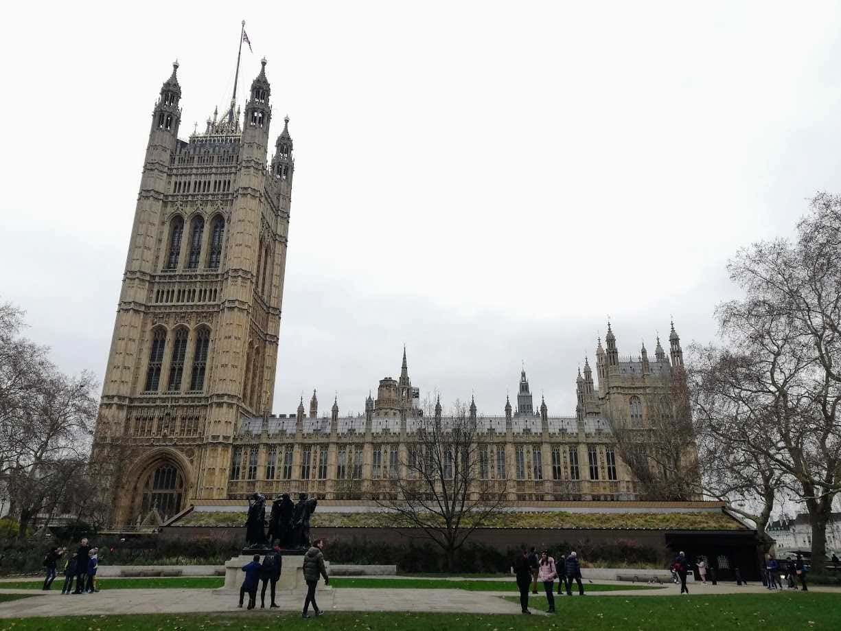 Torri di Westminster a Londra, simbolo dell'architettura gotica, visitato da turisti presso il Parlamento britannico, sotto un cielo grigio in una giornata invernale.