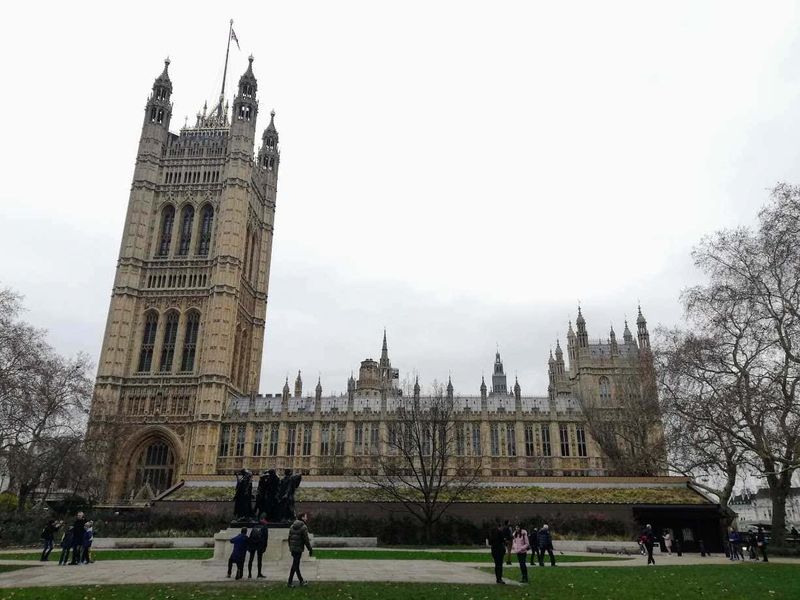 10 Quartieri di Londra a capodanno 4 Torri di Westminster a Londra, simbolo dell'architettura gotica, visitato da turisti presso il Parlamento britannico, sotto un cielo grigio in una giornata invernale.