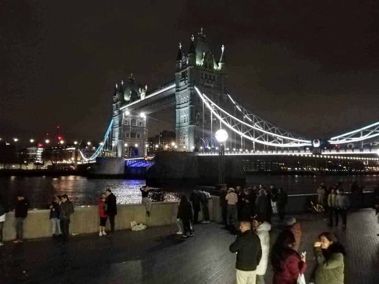 Torri di Londra illuminate di notte. View degli storici monumenti in una serata London Bridge, con persone che passeggiano lungo il fiume Tamigi, creando un'atmosfera vivace e suggestiva, perfetta per un blog di viaggi.