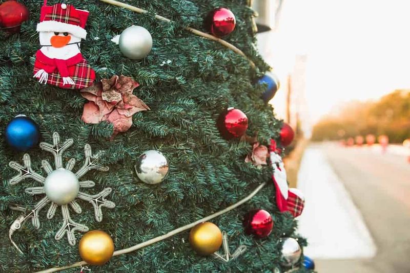 Celebrazione del Natale in Corea del Sud 4 Albero di Natale decorato con palline rosse, oro e argento, fiocchi di neve e calze natalizie in un ambiente all'aperto con luce calda.