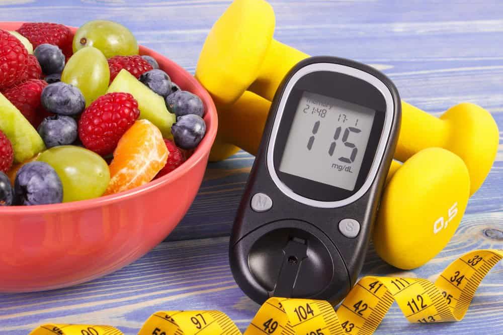 Frutta fresca e glucometro digitale con fettuccia misuratrice, elementi per uno stile di vita sano e monitoraggio della glicemia, concetti chiave per alimentazione equilibrata e salute.