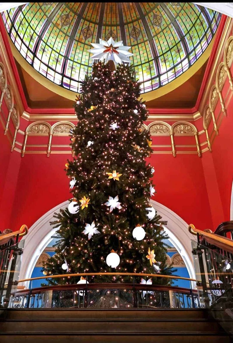 Quando si fa l'albero di Natale in Italia 3 Albero di Natale decorato con luci e ornamenti sotto una cupola di vetro colorata in un salone elegante.