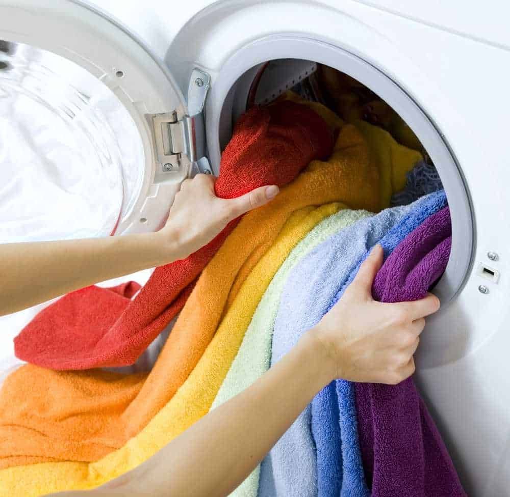 Lavatrice con asciugamani colorati in lavaggio, cura dei tessuti, biancheria colorata, lavaggio a casa, pulizia e cura degli asciugamani di cotone.