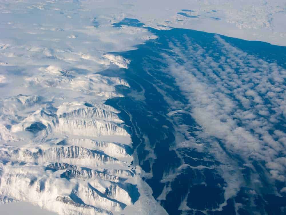 Montagne innevate con ghiacciai e formazione di nubi, paesaggio alpino innevato, primi piani di cime ghiacciate e scarsa visuale del cielo, scenario glaciale e atmosferico in alta quota.