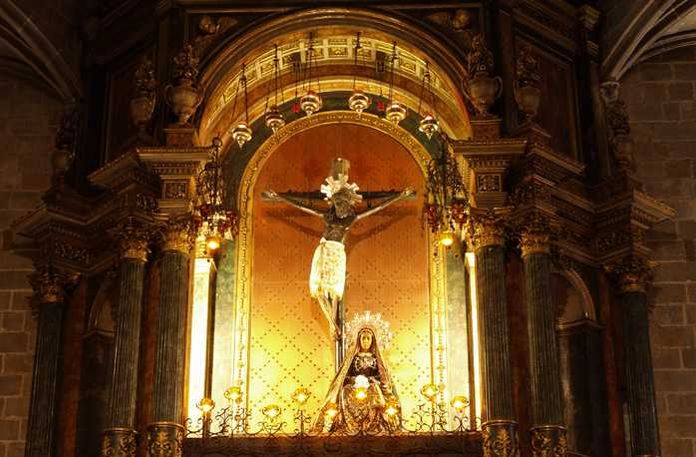 La cattedrale di Barcellona si chiama Santa Eulalia 4 Vedi immagine di un crocifisso e una statua religiosa all'interno di una chiesa storica, con dettagli dorati e un'illuminazione calda, ideale per contenuti religiosi o spirituali.