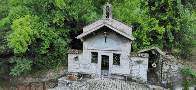 Portico di Romagna il paese di Dante e Beatrice 5 Piccola cappella in pietra con affreschi e fiorellini, circondata da alberi verdi, rivelando un’atmosfera di serenità e spiritualità in un contesto naturale.