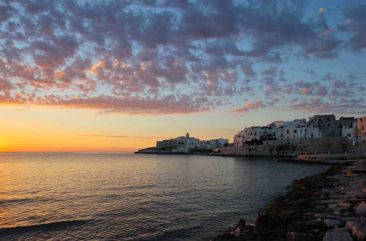 Tramonto sulla costa di Apulia con cielo colorato e paesaggio marittimo.