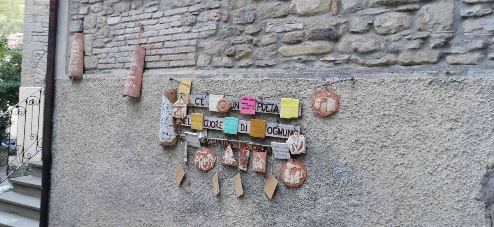 Creativa decorazione su parete con citazioni e ornamenti artigianali in terracotta, proveniente da Appunti Sul Blog, perfetta per ispirare poesia e creatività all'aperto.