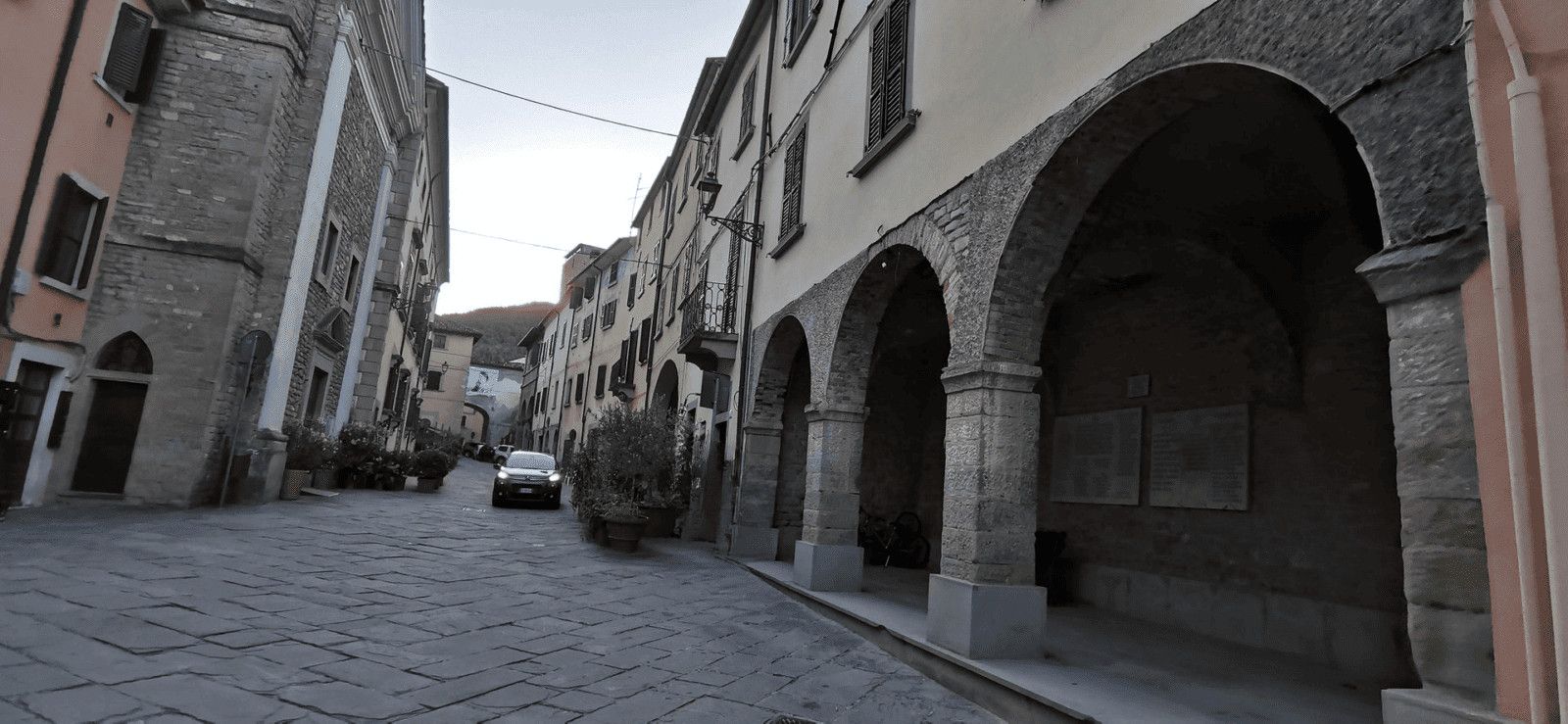 Vecchia strada di pietra con archi in pietra e edifici storici su strada di montagna in Italia, atmosfera tranquilla, architettura antiquata, viaggi in Italia, centro storico.
