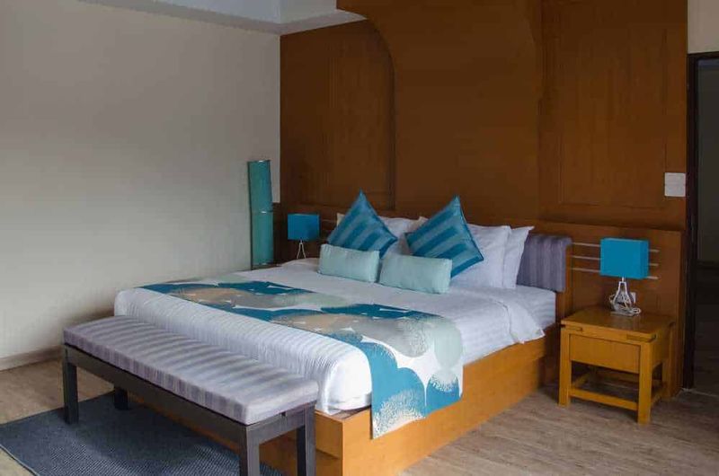 Letti sommier per hotel: design funzionale e accoglienza di qualità 2 Letto sommier per hotel: Lenzuola e cuscini blu su letto in una camera moderna con pareti di legno e lampade da tavolo, arredamento elegante e accogliente, ideale per soggiorni confortevoli in hotel o bed and breakfast.