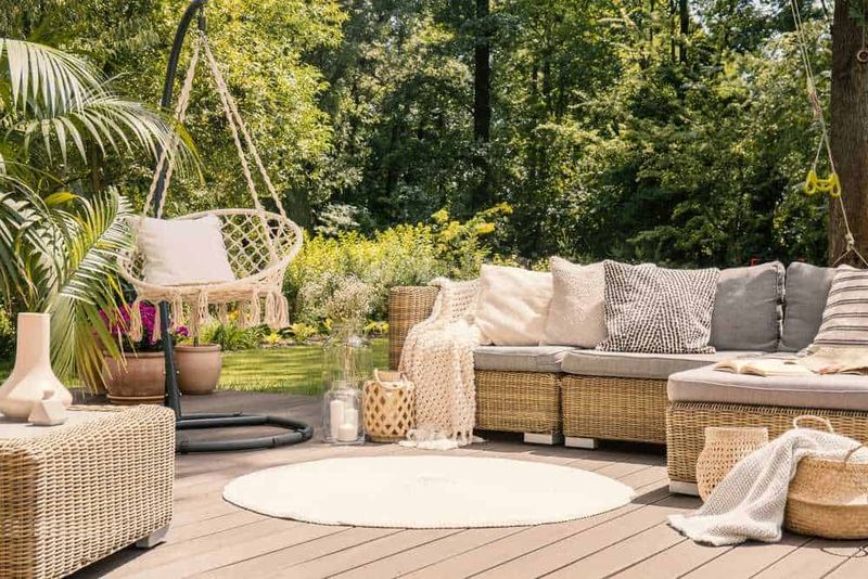 È tempo di arredare il giardino per la bella stagione 4 Relaxing outdoor patio with wicker furniture, hammock swing, lush greenery, and cozy cushions, perfect for outdoor leisure and enjoying nature.