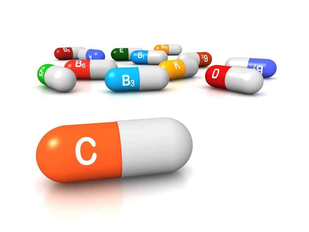 Capsula di medicina con vitamina C e altre vitamine colorate in background, rappresentazione di integratori vitaminici, salute e benessere.