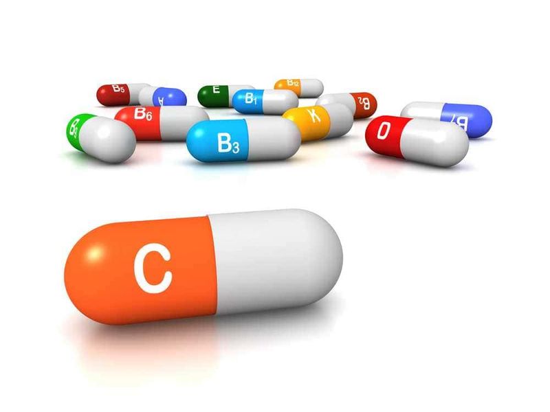 Benefici della vitamina C per la pelle 3 Capsula di medicina con vitamina C e altre vitamine colorate in background, rappresentazione di integratori vitaminici, salute e benessere.