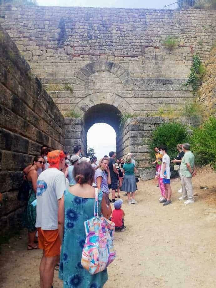 Varco storico con visitatori, escursione e turismo archeologico, scavi e monumenti antichi, visita guidata e cultura, sito archeologico patrimonio mondiale UNESCO, l'antica architettura romana, resti romani e storia antica.