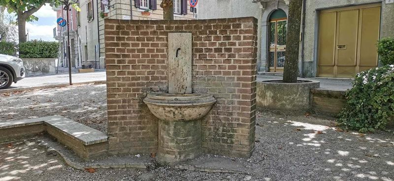 Cosa vedere a Guardiagrele e dintorni Abruzzo 3 Fonte pubblica d'acqua in pietra e mattoni in un cortile urbano, circondata da edifici storici e strade, offre un angolo di tranquillità e storia nel quartiere.