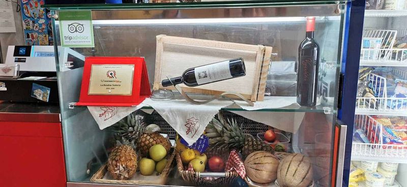 Cosa vedere a Guardiagrele e dintorni Abruzzo 15 Vetrina frigo con frutta, vino, premio e slogan di TripAdvisor, in un negozio alimentare italiano.