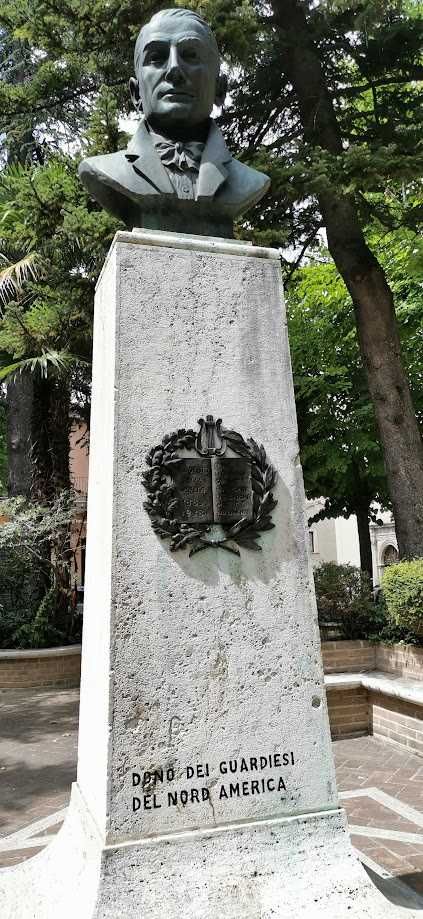 Cosa vedere a Guardiagrele e dintorni Abruzzo 4 Scultura di busto di un uomo su un monumento dedicato ai guardiani del Nord America con un bassorilievo e iscrizione in italiano, collocato in un parco alberato.