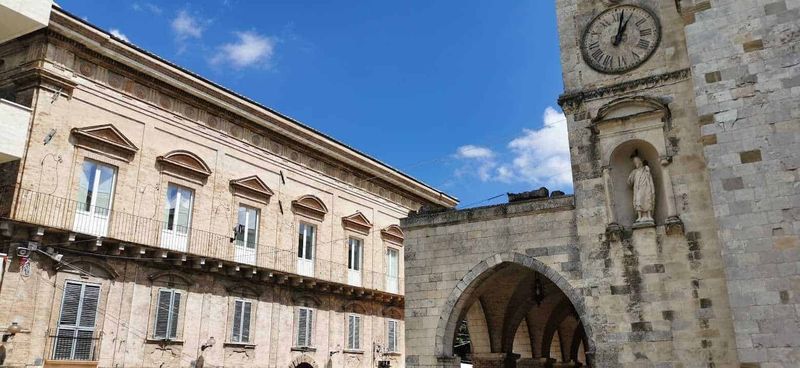 Cosa vedere a Guardiagrele e dintorni Abruzzo 7 Vecchio edificio storico con archi e orologio sulla torre in pietra, documentazione architettonica e culturale con affreschi e decorazioni rinascimentali, situato in Italia, esempio di architettura storica.