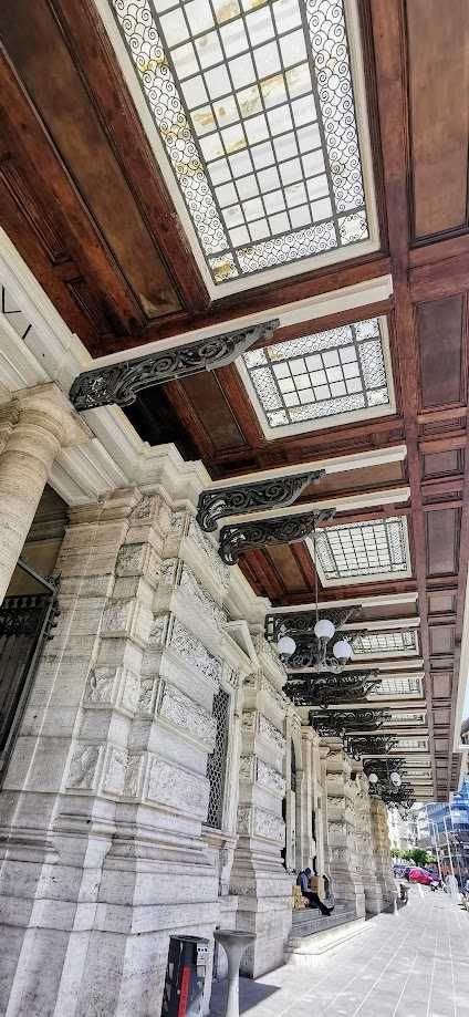 Elegante facciata con finestra decorativa in vetro e ornamenti in ferro battuto su un edificio storico in stile classico.