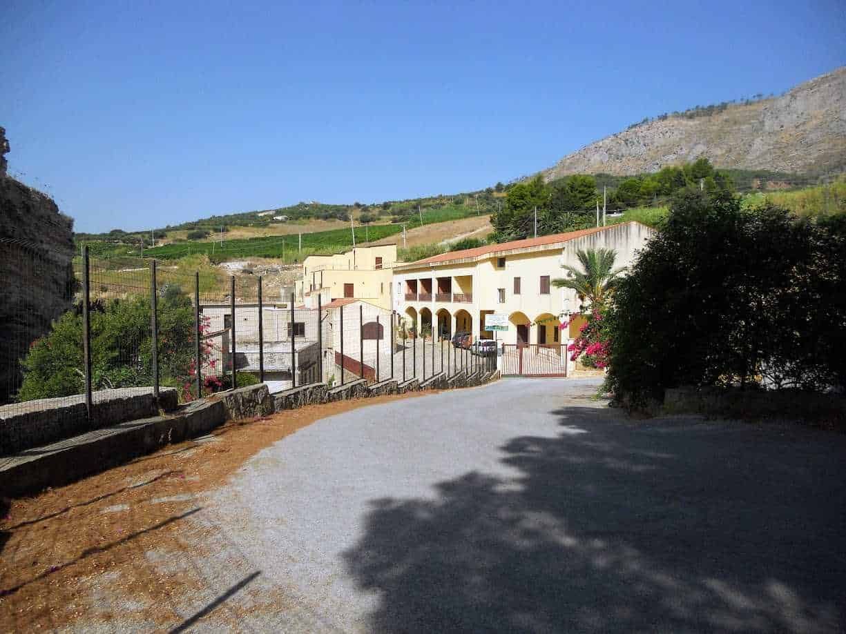 Magazzino storico in stile mediterraneo con archi e balconi, immerso in una pittoresca campagna collinare, circondato da natura e vigneti, ideale per blog di viaggi e lifestyle.