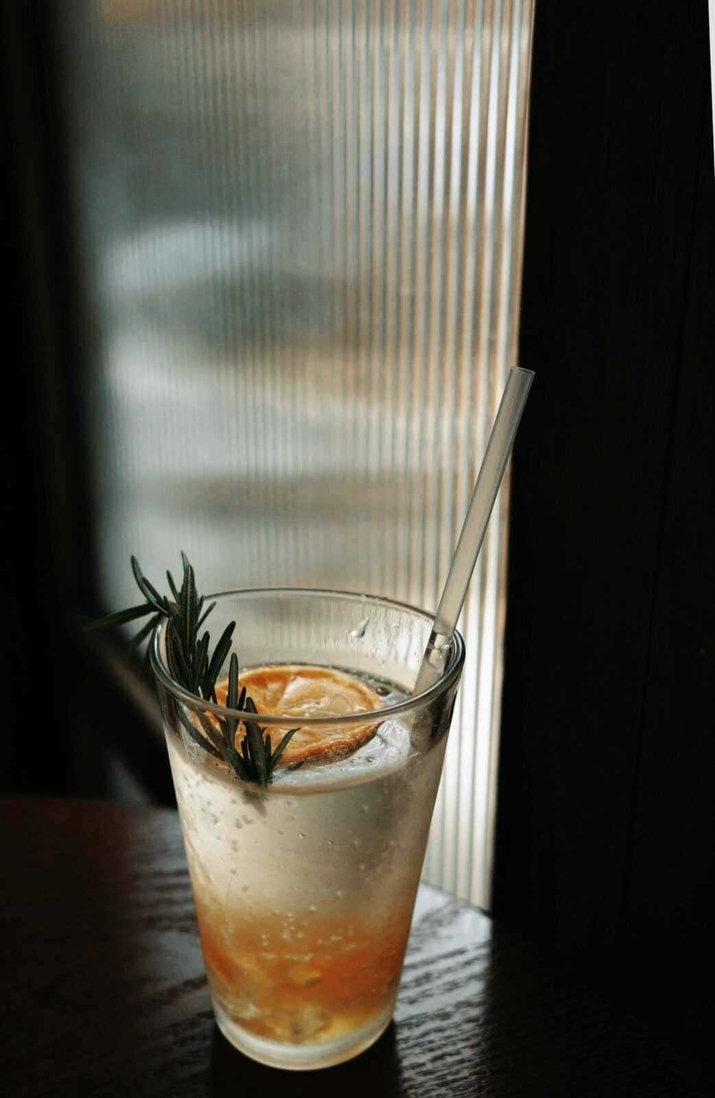 Digestivo rinfrescante con limone, rosmarino e acqua frizzante in un bicchiere trasparente. Perfetto esempio di ricetta di cocktail estivi, ideale per rilassarsi e gustare un drink gustoso tra amici.