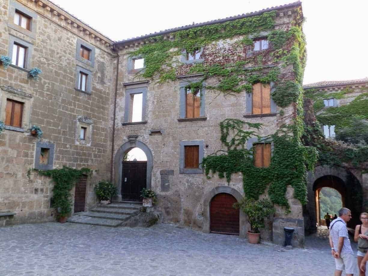 Antico edificio in pietra con piante rampicanti, archi e finestre in legno, atmosfera storica e suggestiva, ideale per appunti sul blog su architettura e turismo in Italia.