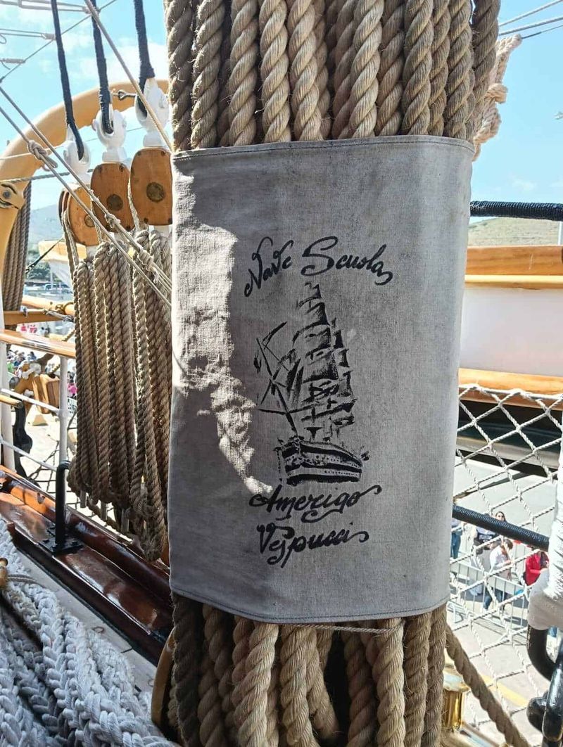 Amerigo Vespucci a Napoli 2025: cosa sapere 14 Tovaglia in tessuto con stampa di un veliero e scritte "Save Seashells, Amo poco, Vesuvio", decorata con corde marinerie, in un contesto marittimo o nautico all'aperto.