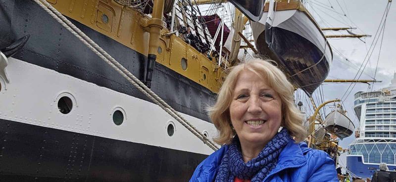Amerigo Vespucci a Napoli 2025: cosa sapere 4 Nave da crociera storica e donna sorridente in primo piano, porto turistico con yacht e barche nel background, turismo marittimo, viaggio e avventure in mare.