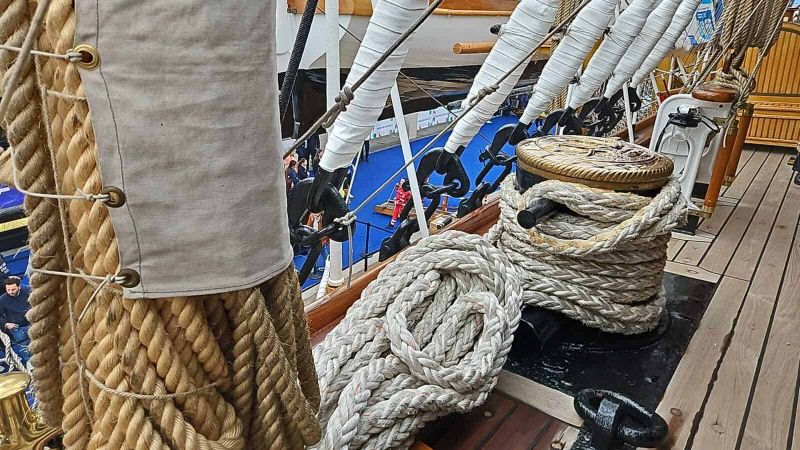 Amerigo Vespucci a Napoli 2025: cosa sapere 11 Corda di varo e ganci di ormeggio su una barca a vela, dettagli su attrezzature nautiche e setup marittimo, materiali robusti e stile nautico vicino al ponte di legno.