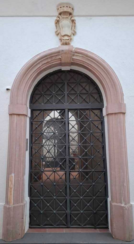 Stili dei portoni a Ravello: dal Medioevo al rustico 7 Escada de ferro battuto davanti a una porta in pietra con arco in stile antico, decorata con dettagli classici e elementi architettonici di pregio. Perfetta per un edificio storico o un'entrata elegante.