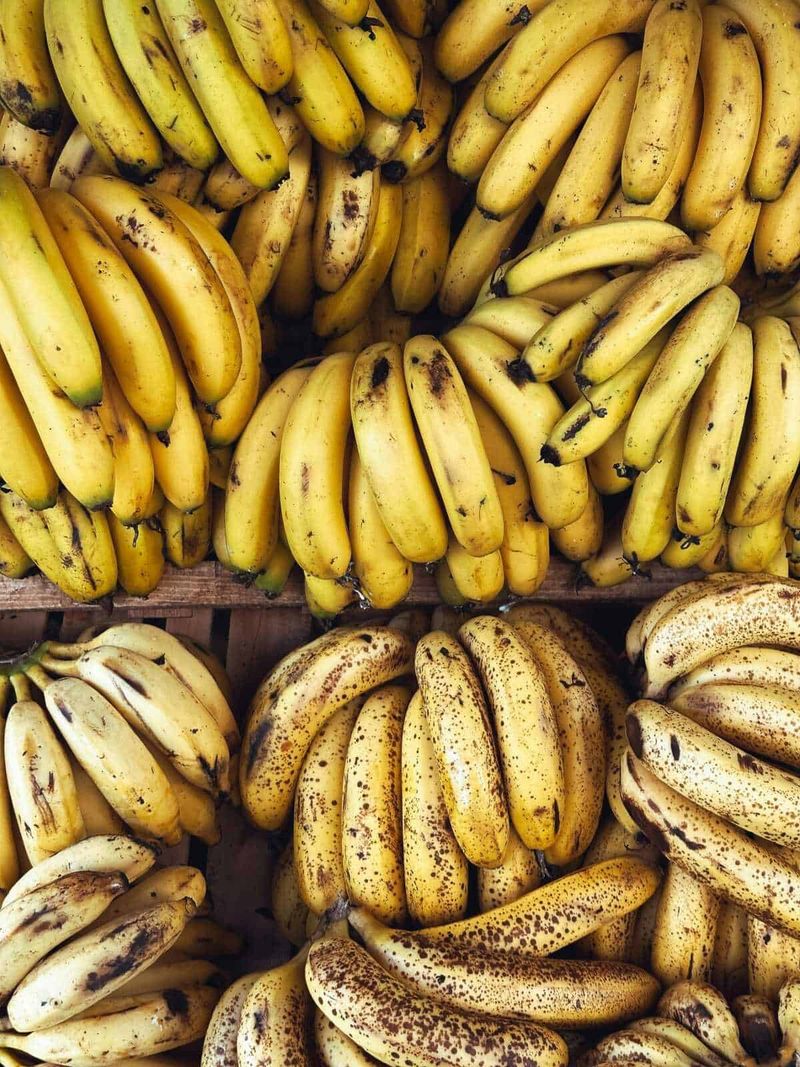 Le banane si devono lavare e perché? 4 Banane fresche e mature vendute al banco del mercato, in diverse varietà e maturazioni, pronte per essere consumate o utilizzate in cucina.