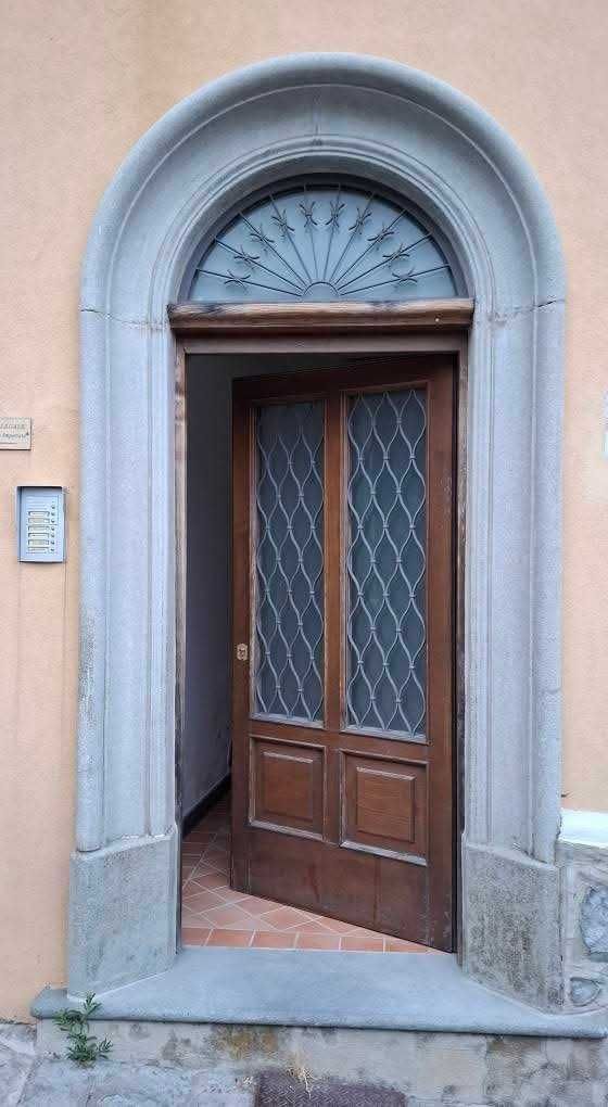 Stili dei portoni a Ravello: dal Medioevo al rustico 9 Porta in stile classico con finestra in vetro decorativo, inserita in un arco di pietra, in un edificio storico italiano.