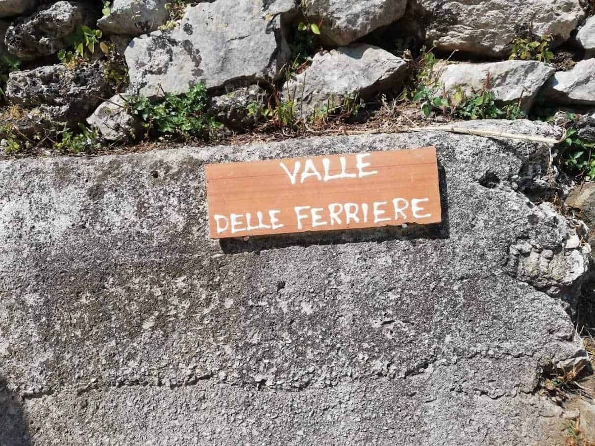 Valle delle Ferriere, segnacolo in legno su muro di pietra, ambientazione naturale, escursioni e trekking in riva alle montagne di Valle.