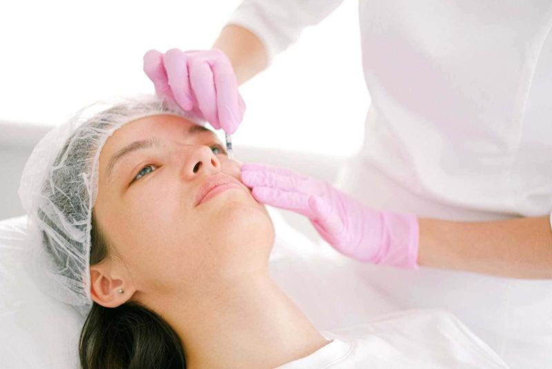 Chirurgia estetica all’Estero: Guida 2025 3 Esame del viso durante trattamento estetico, approccio professionale alla cura della pelle. Procedura di iniezione o trattamento di medicina estetica su una paziente femminile.